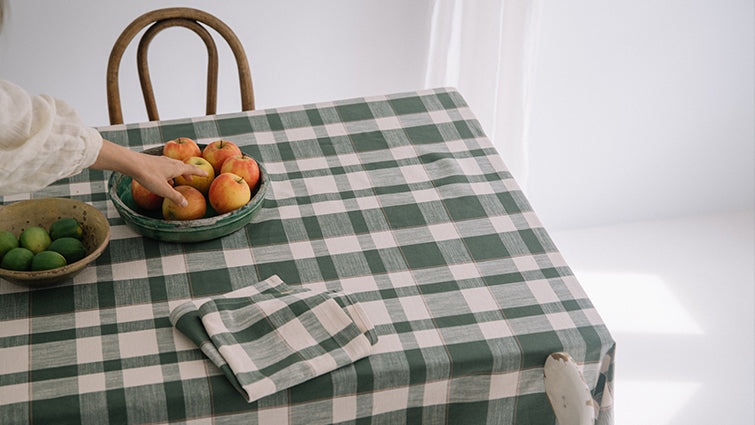 Table avec nappe à carreaux verts et blancs et serviette assortie.